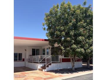 Charming single-story home with a covered front porch, mature trees, and red and white accents at 7750 E Broadway Rd # 604, Mesa, AZ 85208