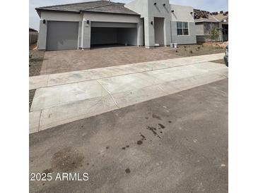 New construction house with a three-car garage and brick paver driveway at 14800 W Lariat Ln, Surprise, AZ 85387