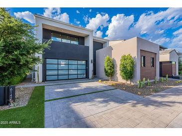Contemporary home featuring a glass garage door, desert landscaping, and a paved driveway at 6142 E Alta Hacienda Dr, Scottsdale, AZ 85251