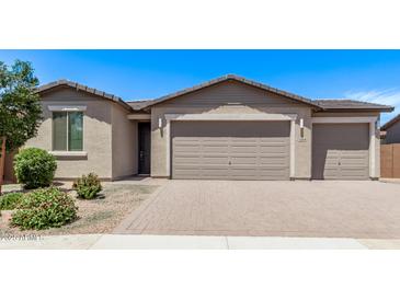 Tan home featuring a two-car garage, beautiful landscaping, and a brick driveway at 1268 E Jahns Dr, Casa Grande, AZ 85122