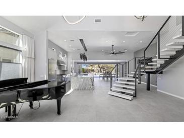 Bright and spacious living room with modern staircase, piano, and kitchen view at 20274 N 76Th Way, Scottsdale, AZ 85255