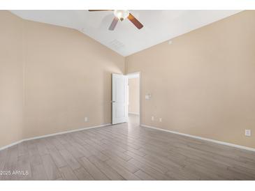 Neutral bedroom showcasing vaulted ceiling, light-tone walls, light tile flooring, and a white paneled door at 22576 N Davis Way, Maricopa, AZ 85138