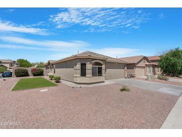 Inviting home boasts a well-manicured lawn, mature plants, and desert landscaping at 22576 N Davis Way, Maricopa, AZ 85138
