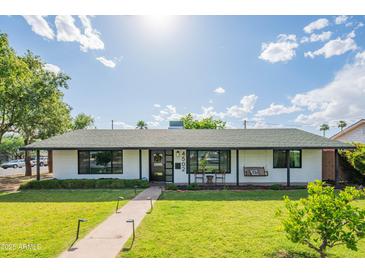 Charming single-story home with a well-manicured lawn, walkway lighting, and a cozy porch swing for relaxing at 4502 N 17Th Ave, Phoenix, AZ 85015