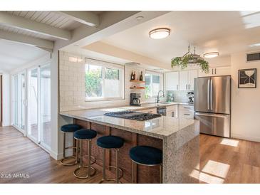 Modern kitchen featuring stainless steel appliances, granite countertops, and a breakfast bar with seating for casual dining at 4502 N 17Th Ave, Phoenix, AZ 85015