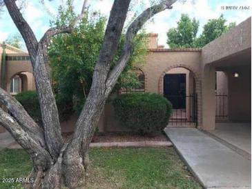 Charming home exterior featuring a covered driveway, desert landscaping, and an arched entryway at 913 E Beryl Ave, Phoenix, AZ 85020