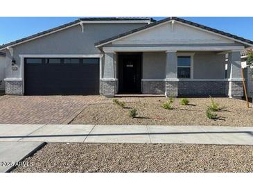Charming single-story home with a well-maintained front yard and a brick-paved driveway at 17677 W Odeum Ln, Goodyear, AZ 85338