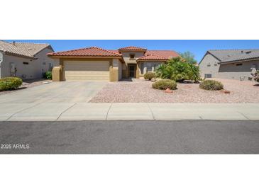 Charming single-story home featuring a well-maintained yard, a two-car garage, and a beautiful red tile roof at 19472 N Marble Canyon Ct, Surprise, AZ 85374