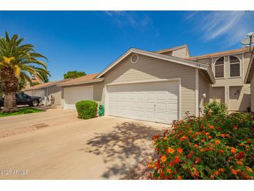 A well maintained townhome garage featuring a white door, adjacent to a blooming flower bed and palm tree at 3134 E Mckellips Rd # 139, Mesa, AZ 85213