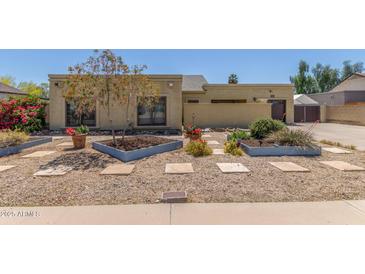 Inviting single-story home featuring xeriscape landscaping, mature trees, and stone walkway at 4233 W Michigan Ave, Glendale, AZ 85308