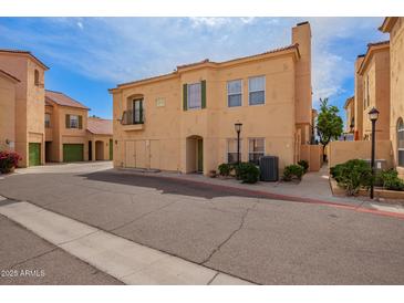 Beige two-story condo featuring a balcony, shuttered windows, and a quaint chimney against a blue sky backdrop at 5015 E Cheyenne Dr # 31, Phoenix, AZ 85044