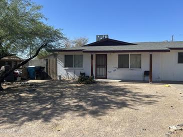 Modest home featuring a low, gabled roof and a gravel front yard against a bright, clear blue sky at 520 W Mcneil St, Phoenix, AZ 85041
