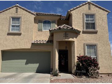 Charming two-story home featuring a quaint front door with a covered entryway and a well-maintained front yard at 703 N Redwood Ln, Buckeye, AZ 85326