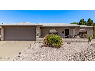 Charming single-story home featuring desert landscaping, gray brick accents and covered front entry at 7904 E Madero Ave, Mesa, AZ 85209