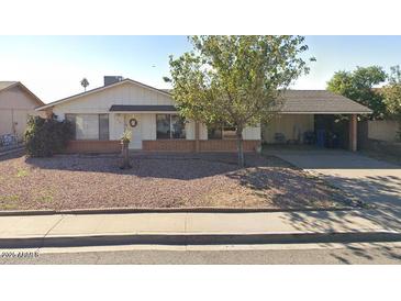 Charming single-story home featuring a welcoming facade, mature trees, and a covered carport at 8741 W Osborn Rd, Phoenix, AZ 85037