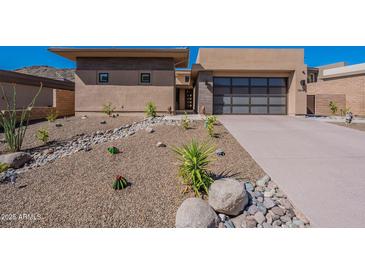 Contemporary home featuring desert landscaping with a concrete driveway and a full glass garage door at 14141 E Highland Ave, Fountain Hills, AZ 85268