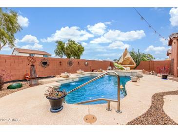 Backyard swimming pool with water features surrounded by a decorative brick fence and lounge seating area at 18482 W Marconi Ave, Surprise, AZ 85388