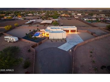 Sprawling property with a private pool, horse stables, and a long driveway at dusk at 2609 W Lavitt Ln, Phoenix, AZ 85086