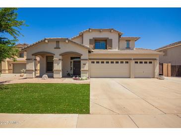 Charming two-story home with well-manicured lawn and a spacious three-car garage on a sunny day at 34949 N Spur Cir, San Tan Valley, AZ 85144