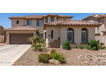 Beige two-story home with a brown roof, lush landscaping, and a two-car garage at 6870 S Crestview Dr, Gilbert, AZ 85298