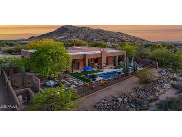 Desert home featuring a large pool, landscaping, and mountain views at sunset at 8300 E Lone Mountain Rd, Scottsdale, AZ 85266