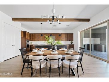 Open concept dining room with modern light fixture, wood beams, and dining table set for dinner at 10134 E Talon Ave, Mesa, AZ 85212