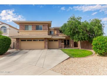 Two-story home with a well-manicured lawn, three car garage and brick accents at 15910 W Shangri La Rd, Surprise, AZ 85379