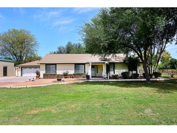 Charming single-story home with green lawn, mature trees, and neutral toned facade at 17730 E Brooks Farm Rd, Gilbert, AZ 85298