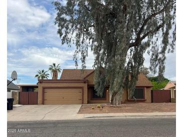 Charming single-story home with desert landscaping, a two-car garage, and a mature shade tree at 1110 E Utopia Rd, Phoenix, AZ 85024