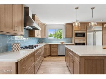 Well-lit kitchen boasts custom cabinetry, stainless steel appliances, and a center island with quartz countertop at 14802 N 3Rd Ave, Phoenix, AZ 85023