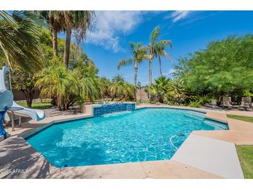 Beautiful backyard pool featuring palm trees and a built-in water feature, perfect for relaxation and entertainment at 2160 E Kenwood St, Mesa, AZ 85213