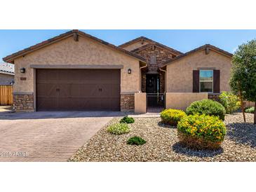Charming single-story home featuring a stone-accented entrance, desert landscaping, and a brick paver driveway at 2229 N 139Th Dr, Goodyear, AZ 85395