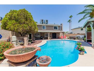 Inviting backyard oasis with a sparkling pool, hot tub and lush landscaping, perfect for outdoor entertaining at 3377 W Grandview Rd, Phoenix, AZ 85053