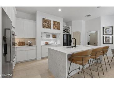 Modern white kitchen boasts marble countertops, stainless steel appliances, and seating at the island at 8974 E Rusty Spur Pl, Scottsdale, AZ 85255