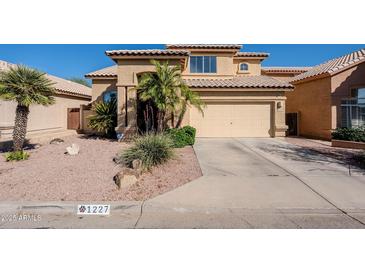 Inviting tan two-story home featuring a two-car garage, desert landscaping, and a tile roof at 1227 E Sheena Dr, Phoenix, AZ 85022