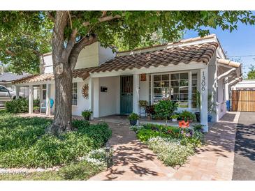 Charming home featuring a tile roof, lush landscaping, and a welcoming brick pathway leading to the front door at 1306 W Heatherbrae Dr, Phoenix, AZ 85013