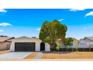 Charming single-story home with a well-manicured front yard and dark grey two-car garage at 1615 E Fremont Dr, Tempe, AZ 85282