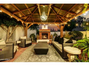Cozy backyard patio with fireplace, seating, and chandelier lighting at 4833 N 38Th St, Phoenix, AZ 85018