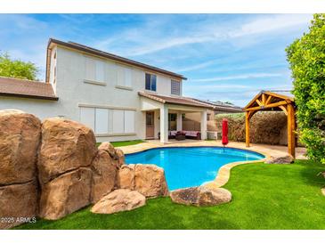 Stunning backyard with a rock feature by the pool, gazebo and covered patio with comfortable outdoor seating at 18171 W Marshall Ln, Surprise, AZ 85388