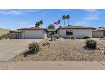 Charming single-story home featuring desert landscaping, palm trees, and American flag at 4913 E Acoma Dr, Scottsdale, AZ 85254