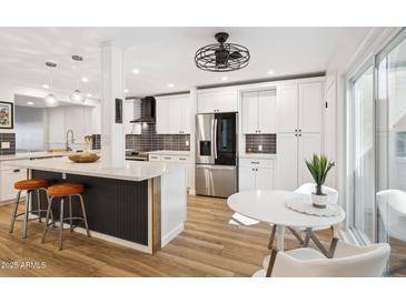 Bright updated kitchen with white cabinetry, stainless appliances, pendant lighting and an island with seating at 7214 N Via De La Siesta --, Scottsdale, AZ 85258