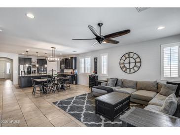 Open concept living room with gray sectional, stylish rug, kitchen island and dining table at 7634 W Redbird Rd, Peoria, AZ 85383