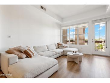 Bright living room with a sectional sofa, natural light, and balcony access at 14575 W Mountain View Blvd # 11308, Surprise, AZ 85374