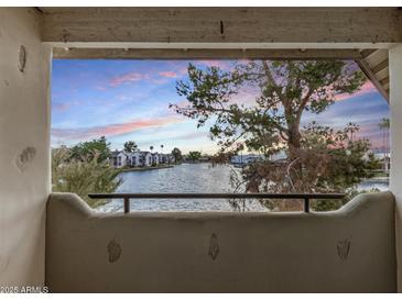 Scenic balcony view overlooking the tranquil waterfront with lush greenery and peaceful homes at sunset at 1825 W Ray Rd # 2111, Chandler, AZ 85224