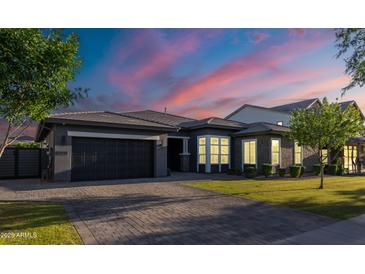 Beautiful home exterior featuring a paved driveway and well-manicured lawn at dusk at 3145 E Boot Track Trl, Gilbert, AZ 85296