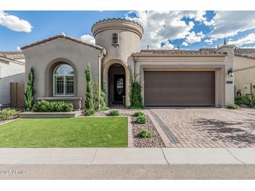 Charming single Gathering home featuring a two-car garage, manicured lawn, and distinctive turret entry at 5653 E Sayan St, Mesa, AZ 85215
