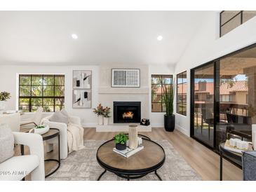 Bright living room featuring a fireplace, recessed lighting, wood floors, and large windows at 8700 E Mountain View Rd # 2011, Scottsdale, AZ 85258