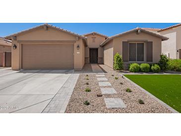 Charming single-story home featuring a well-manicured front yard and a two-car garage at 233 W Sweet Shrub Ave, San Tan Valley, AZ 85140