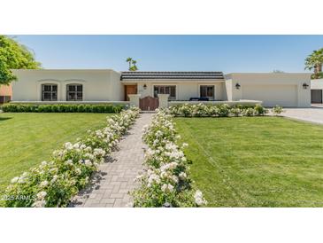 Charming single-story home with a beautiful lawn and walkway lined with white roses leading to the front door at 5711 E Corrine Dr, Scottsdale, AZ 85254