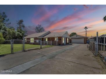Charming single-story brick home featuring a secure fenced yard and long driveway at 618 N Stapley Dr, Mesa, AZ 85203